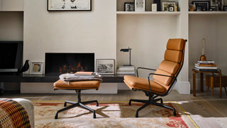 Sfeerbeeld van de Vitra Eames Soft Pad EA 223 voetenbank en loungestoel in cognac bij een haard