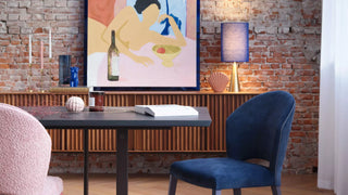 Sfeerbeeld van roze en blauwe Mobitec Cuori stoelen aan een tafel met dressoir en lamp