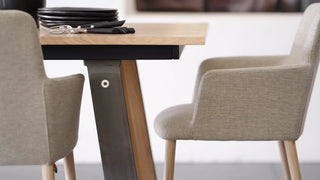 Detail van lichtgrijze Mobitec Rob armstoelen aan een houten tafel met zwart onderstel
