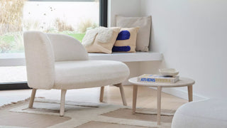 Photo d'ambiance d'une banquette Mobitec Thalia écrue avec coussins et table basse dans un salon lumineux