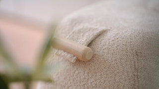 Close-up van de bouclé stof van een Mobitec Thalia poef met houten handgreep