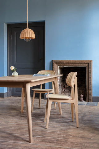 Sfeerbeeld van Vincent Sheppard Titus eetstoelen aan een houten tafel voor een blauwe muur met haard