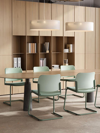 Sfeerbeeld van mintgroene Bejot Volo sledestoelen aan een houten tafel met boekenkast
