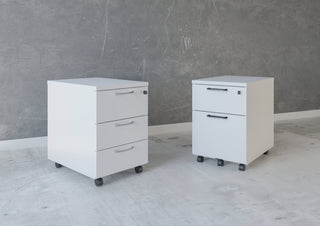White Buronomic Comfort mobile pedestals with two and three drawers against a concrete wall