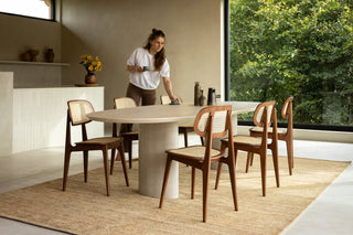 Sfeerbeeld van een vrouw die de tafel dekt met Vincent Sheppard Titus eetstoelen rond een ovale tafel