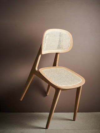 Vincent Sheppard Titus eetstoel in natural oak, schuin voor een bruine wand