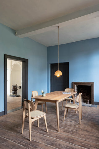 Sfeerbeeld van Vincent Sheppard Titus eetstoelen aan een houten tafel in een blauwe kamer
