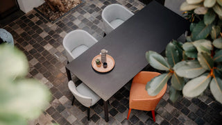 Sfeerbeeld van grijze en oranje Mobitec Cuori stoelen aan een donkere tafel, bovenaanzicht