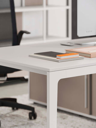 Detail van de hoek van een wit Frezza Alplus bureau met boeken en zwarte stoel